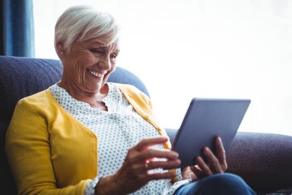 Oudere dame is content met informatie op de sociaal domein-website die ze bekijkt op haar iPad.