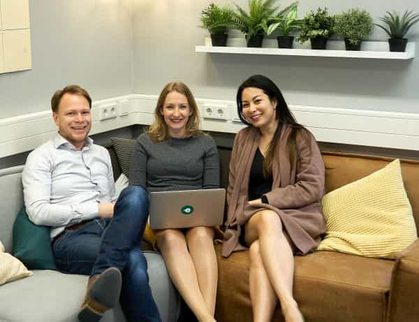 Foto van de accountmanagers van Elkander, met z'n drieën op een bank, terwijl de middelste een laptop op schoot houdt.