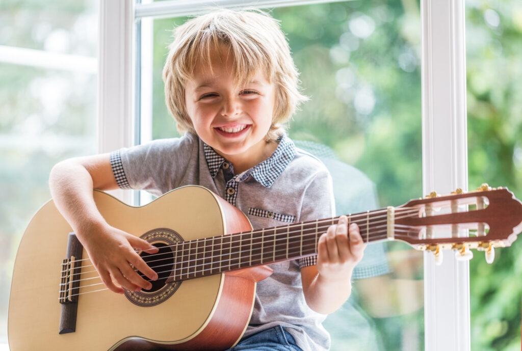 Blije kleine jongen met klassieke gitaar