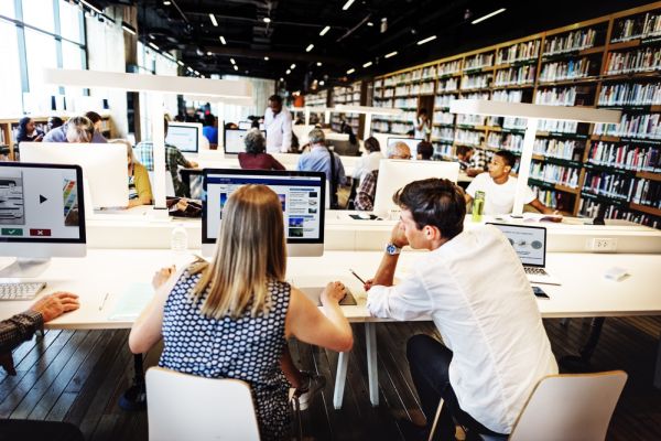 2 mensen zitten achter een pc in een mediatheek